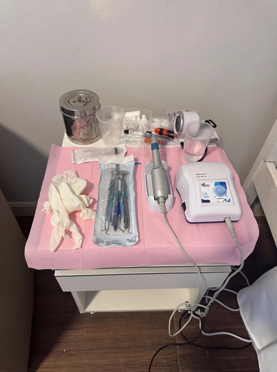 Campo estéril montado sobre mesa portátil na casa do paciente, com instrumentos esterilizados, micromotor e materiais descartáveis
